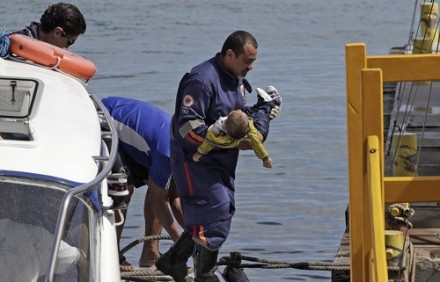 Socorrista do Samu leva um bebê no colo após uma embarcação naufragar em Mar Grande